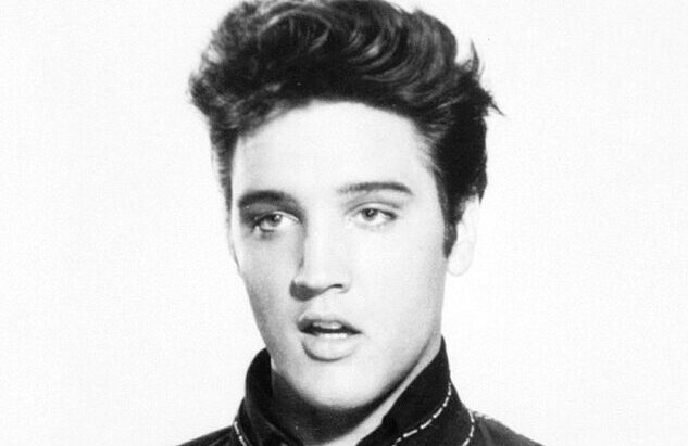 Black and white picture of a young, half-smiling Elvis Presley.