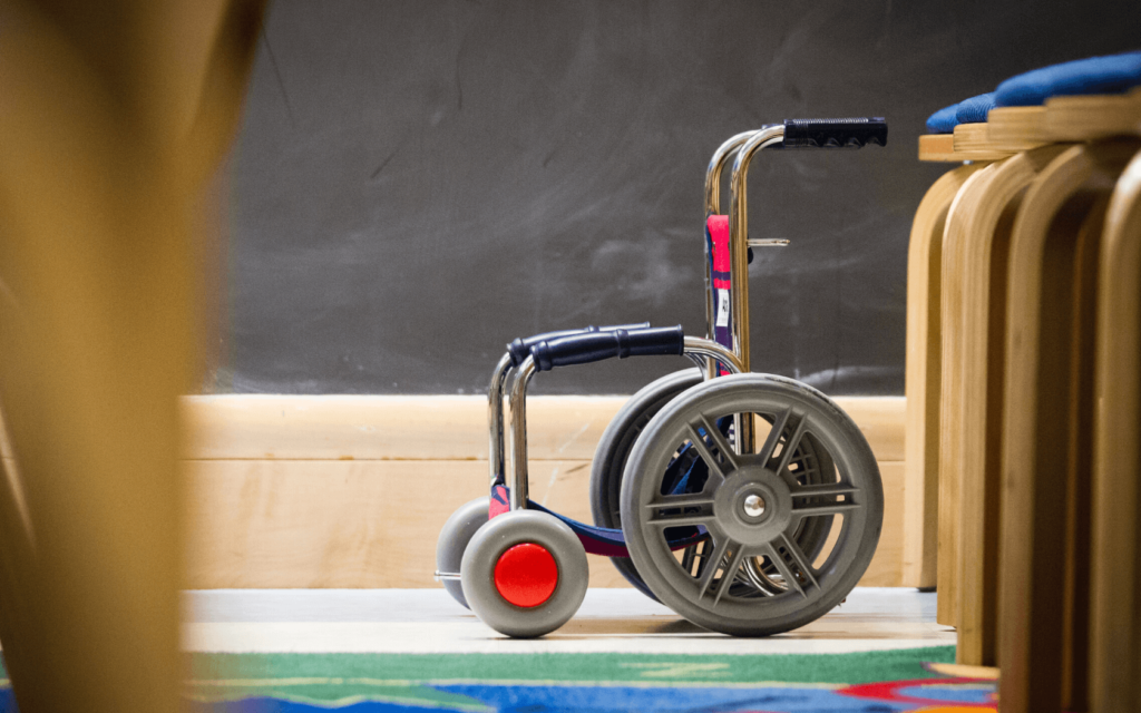 A child's wheelchair with colorful red wheels.