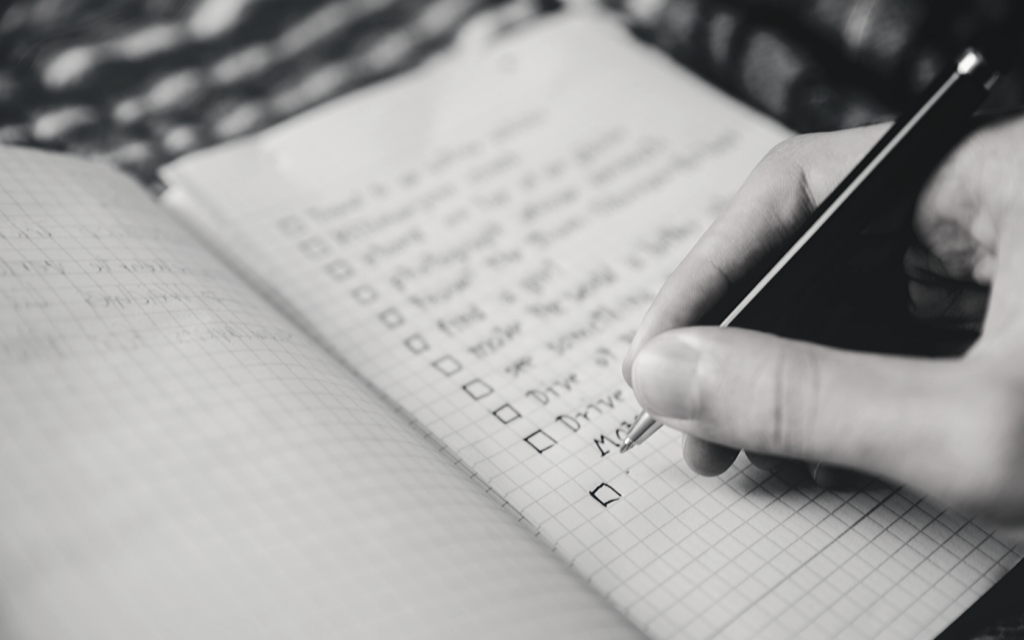 A man writes bullet points in his journal, to be help him remember everything he needs to communicate.