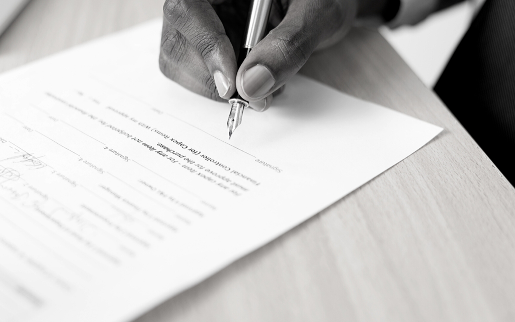 A person signs a legal document with a pen.