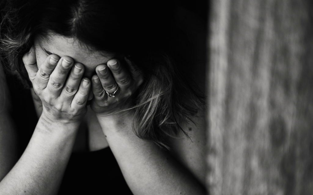 A woman who has experienced pain and suffering from a malpractice case holds her face in the palm of her hands. 