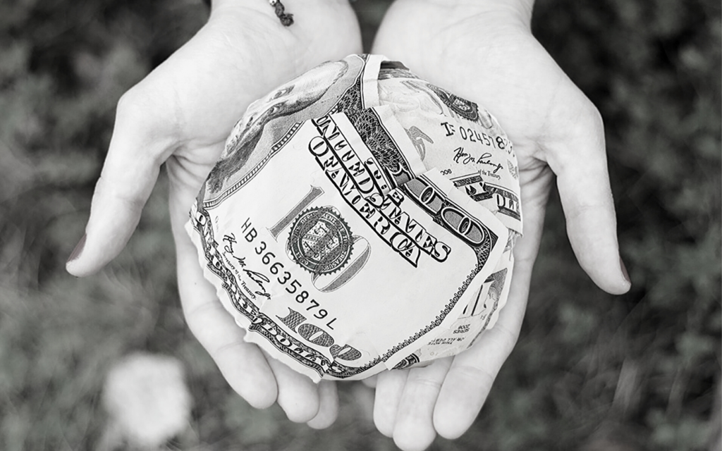 A woman holds a ball of money in the palms of her hands.