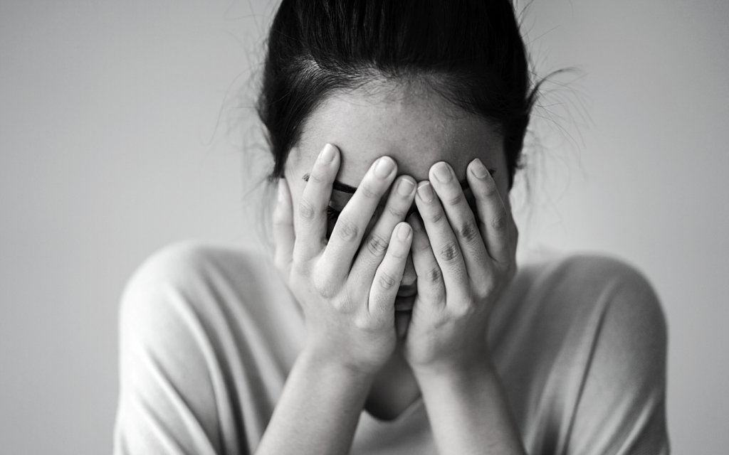 A woman with her hands covering her face in despair. 