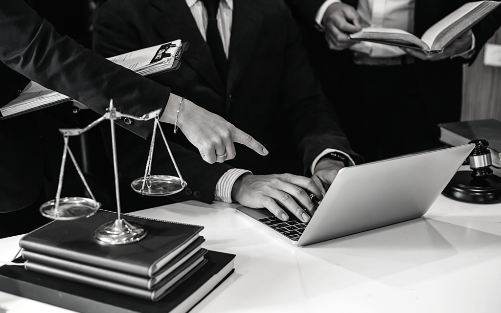 A group of birth injury lawyers look at a laptop while working together on a case. 