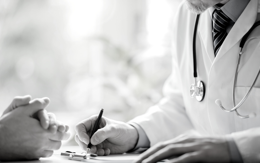 A doctor scribbles down notes while discussing results to patient. 