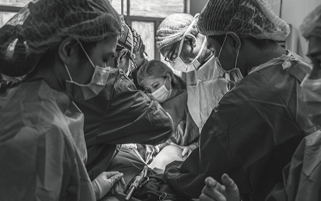 A patient undergoes surgery in a room full of doctors and staff. 