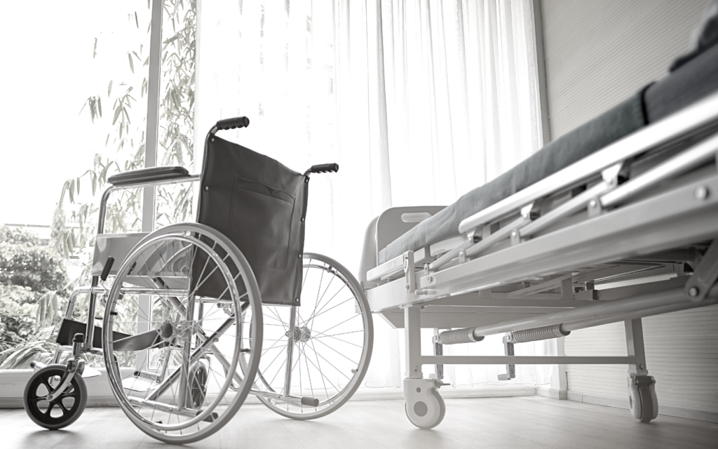 Hospital room with wheelchair next to bed.