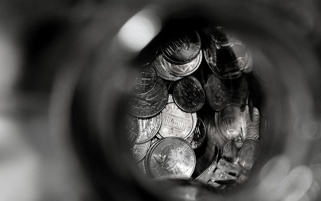 A black and white photo of a jar full of coins. 