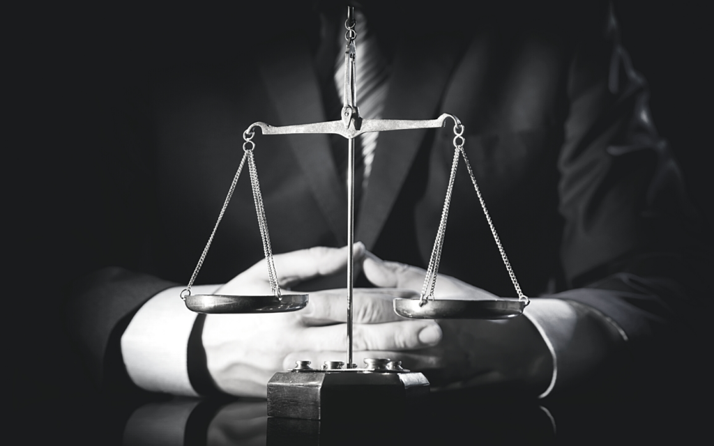 A medical malpractice attorney sits at his desk with the scales of justice propped in front of his hands.