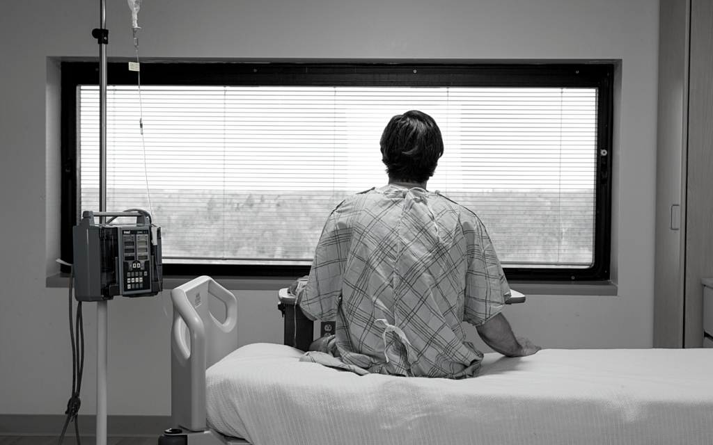 A medical malpractice victim stares out his hospital window.