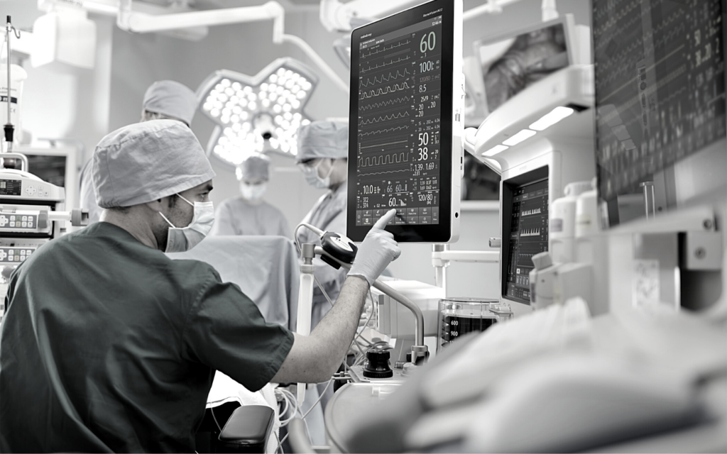 A doctor looks at a computer screen to monitor a patient's condition during surgery. 