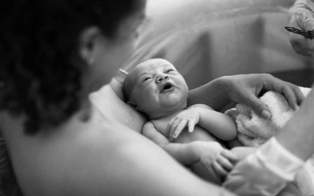 A newborn baby is held in its mothers arms. 
