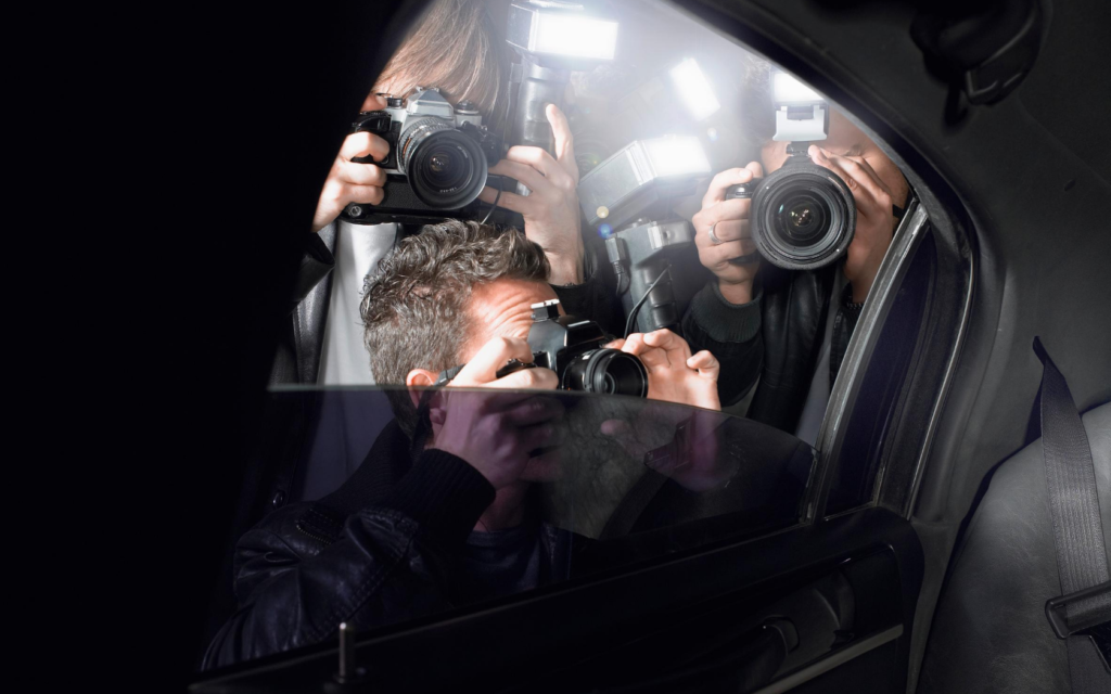A group of paparazzi peer into the car of a famous person. 