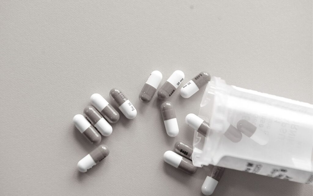 A pill container spills capsules onto a desk.