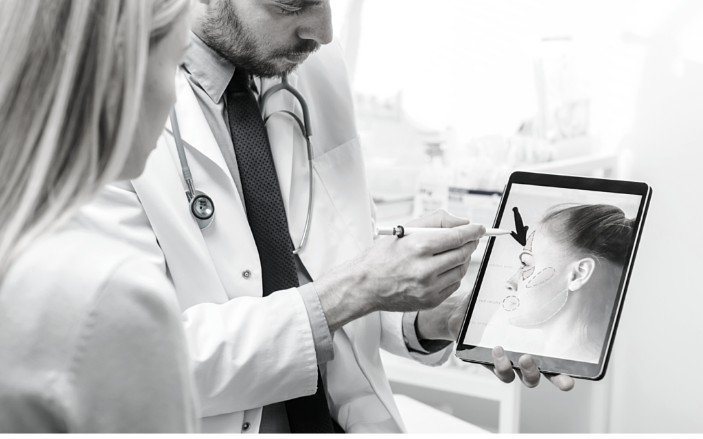 A plastic surgeon showing a patient what she'll look like after surgery on a tablet.