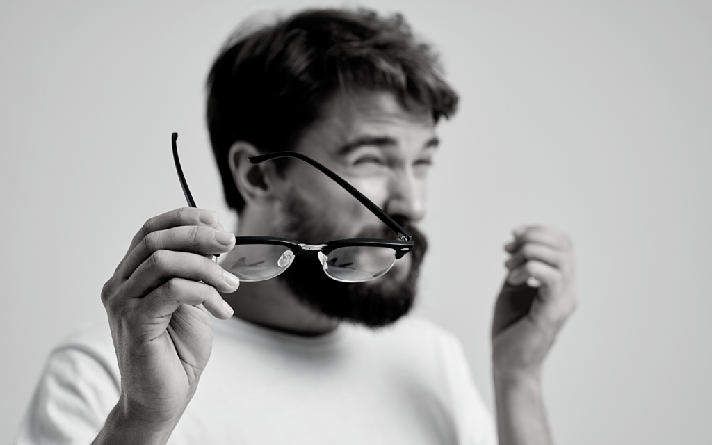 Man holding glasses with poor vision after lasik.