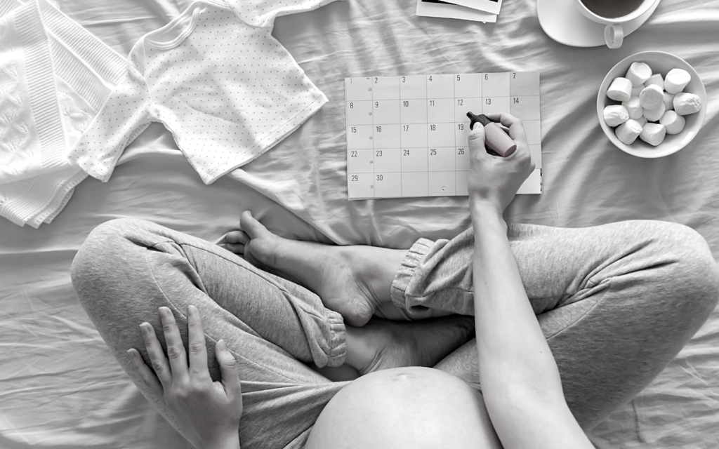Pregnant mother marking on a calendar, presumably her baby's due date.