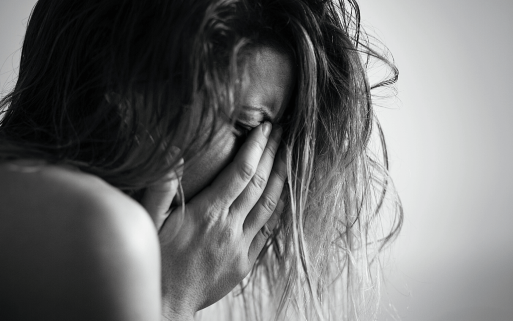 A woman cries with her hands covering her face. 