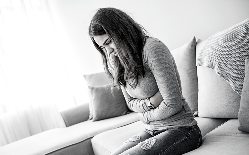 Black and white photo of a woman holding her stomach in pain.