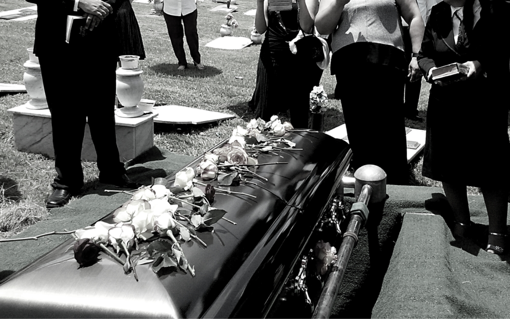 Family around a coffin holding a loved one during funeral. 