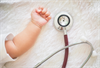 Stethoscope lying next to a baby's arm