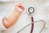 Baby's hand making fist, next to stethoscope.