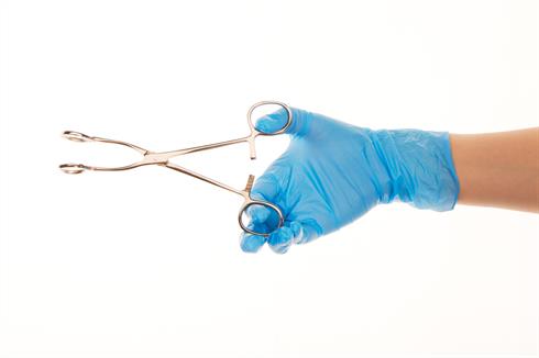 A hand wearing blue surgical gloves holding forceps.