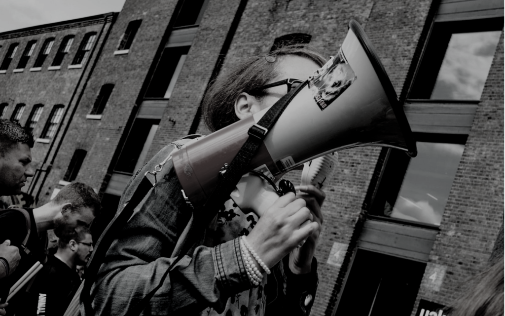 Girl holding a megaphone in front of a crowd.