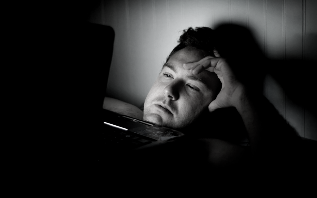 Man searching on a laptop with hand on forehead.