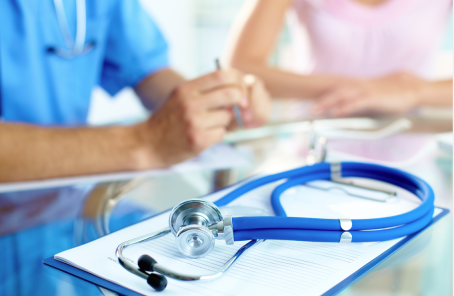 Blue stethoscope and medical records on the table with doctor and nurse in the background.