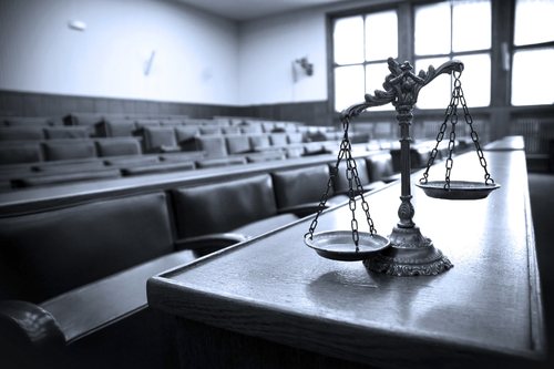 Scales of justice on table at the front of courtroom.