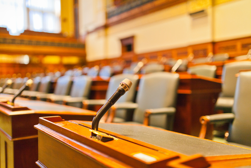 Wooden plaintiff and defendant desks with microphones in courtroom.