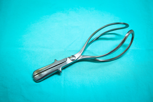 Steel forceps lying on a operating table with a blue background