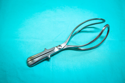 Steel medical forceps laying on a blue sheet. 