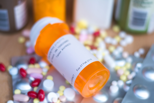 Pill bottle lying on a table with scattered pills all around it