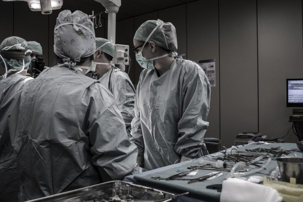 Group of surgeons and medical professionals standing near table.