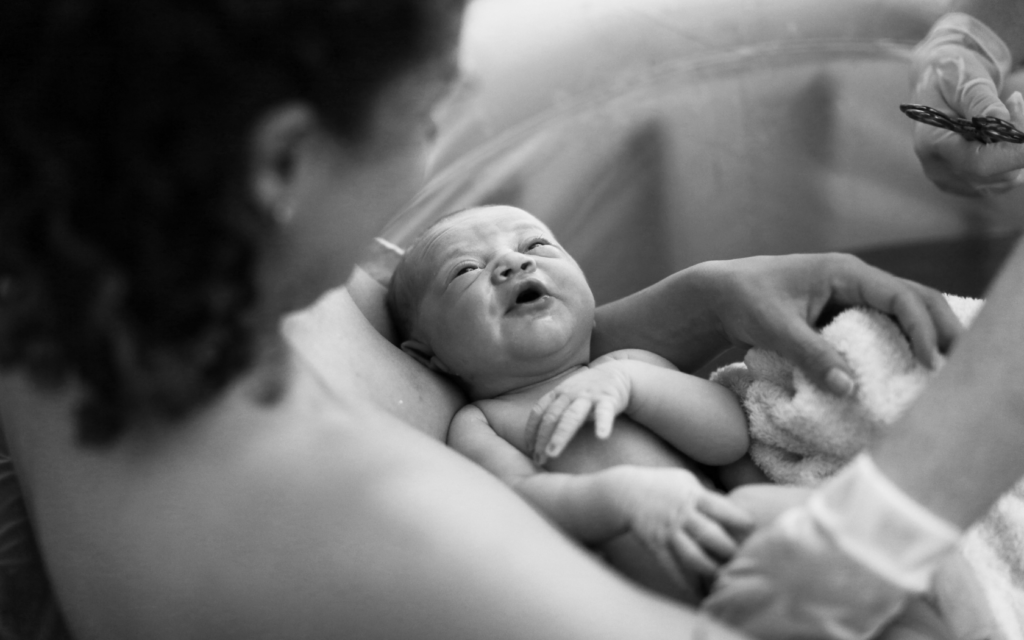Newborn baby looks up at mother. 