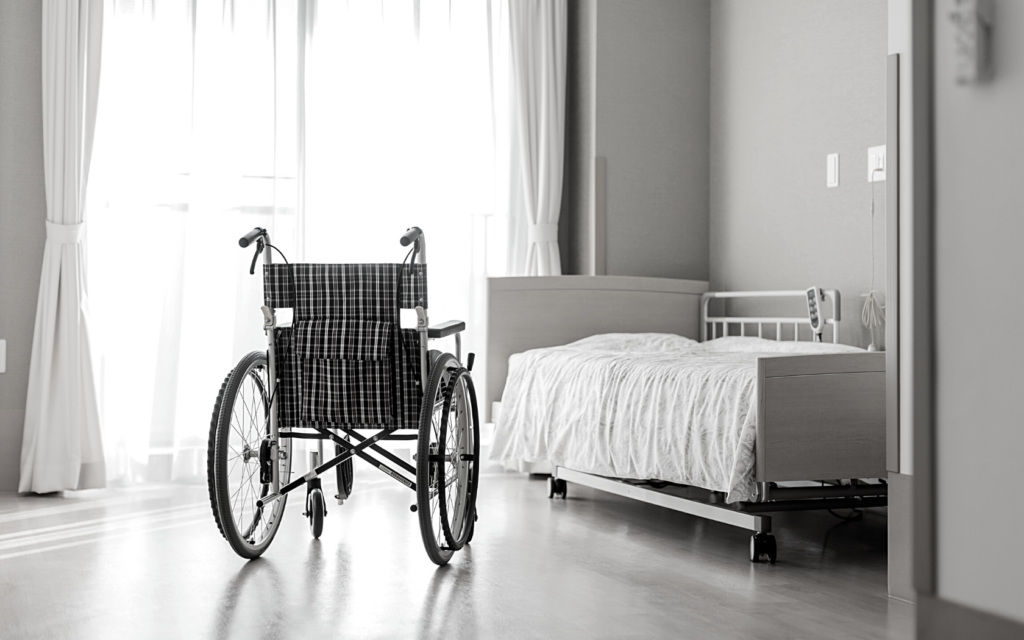 Empty bed and wheelchair in nursing home.
