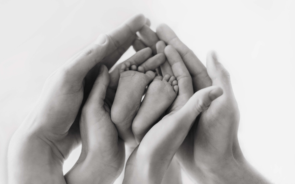 A mother and father hold baby's feet in their hands.