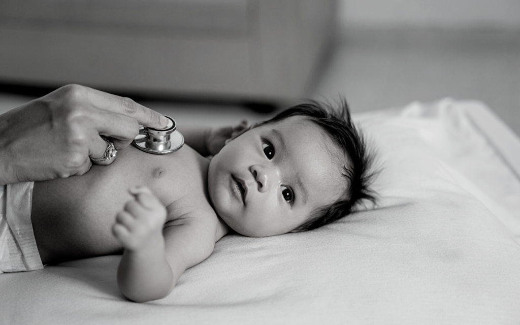 Pediatrician checking baby's heartbeat.