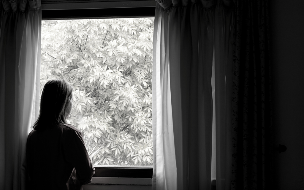 Woman with malpractice injury stares out of a window.