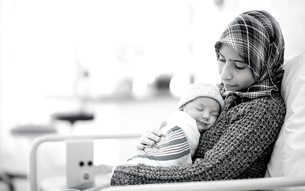 Mother cradles her baby in hospital bed.