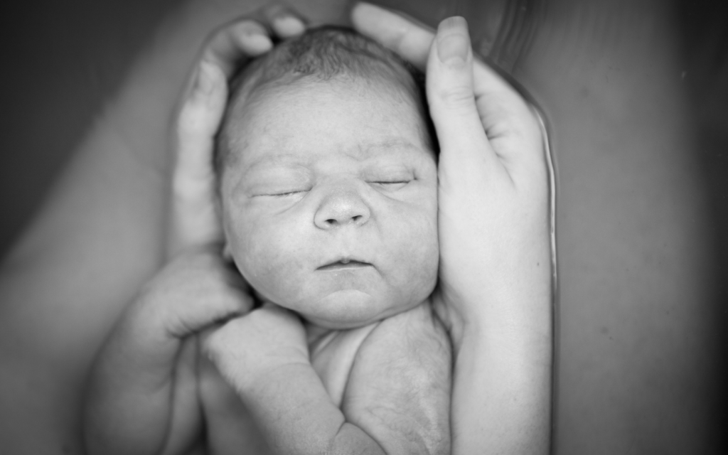 Newborn aby being held by his mother.