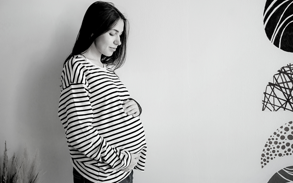 Mother cradles her pregnant belly.