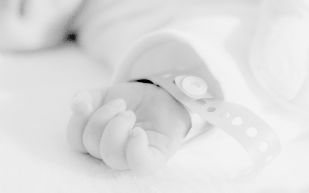 Closeup of baby's hand in NICU incubator.