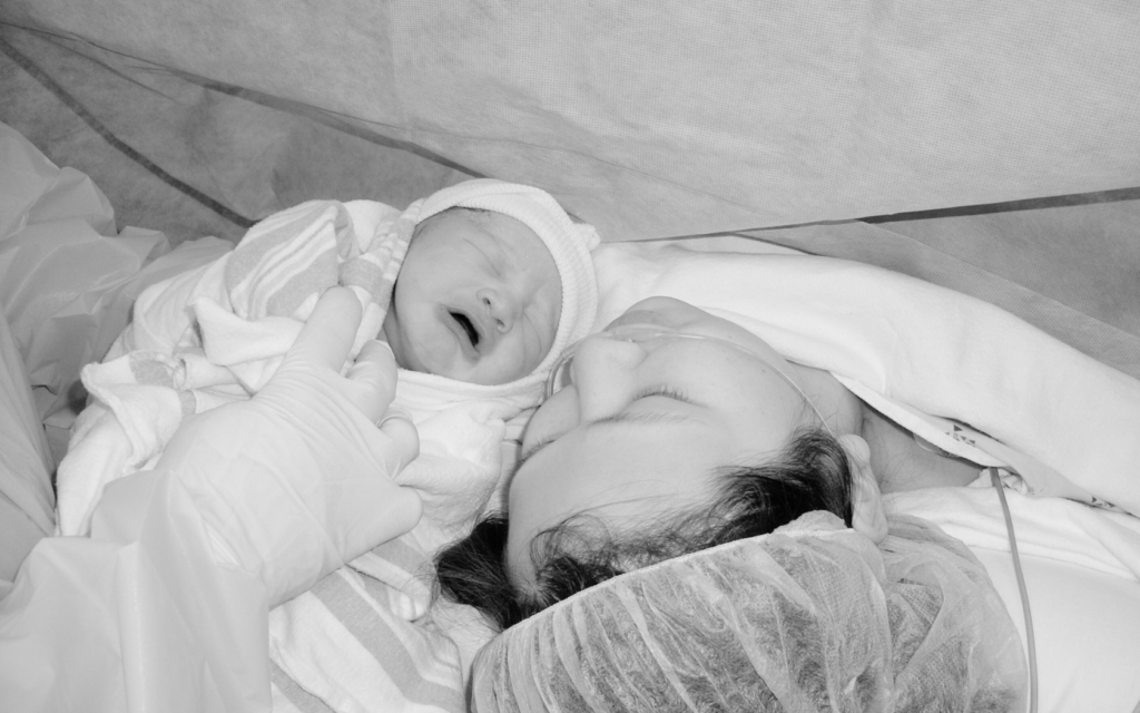 Mother holds her baby after c-section delivery.