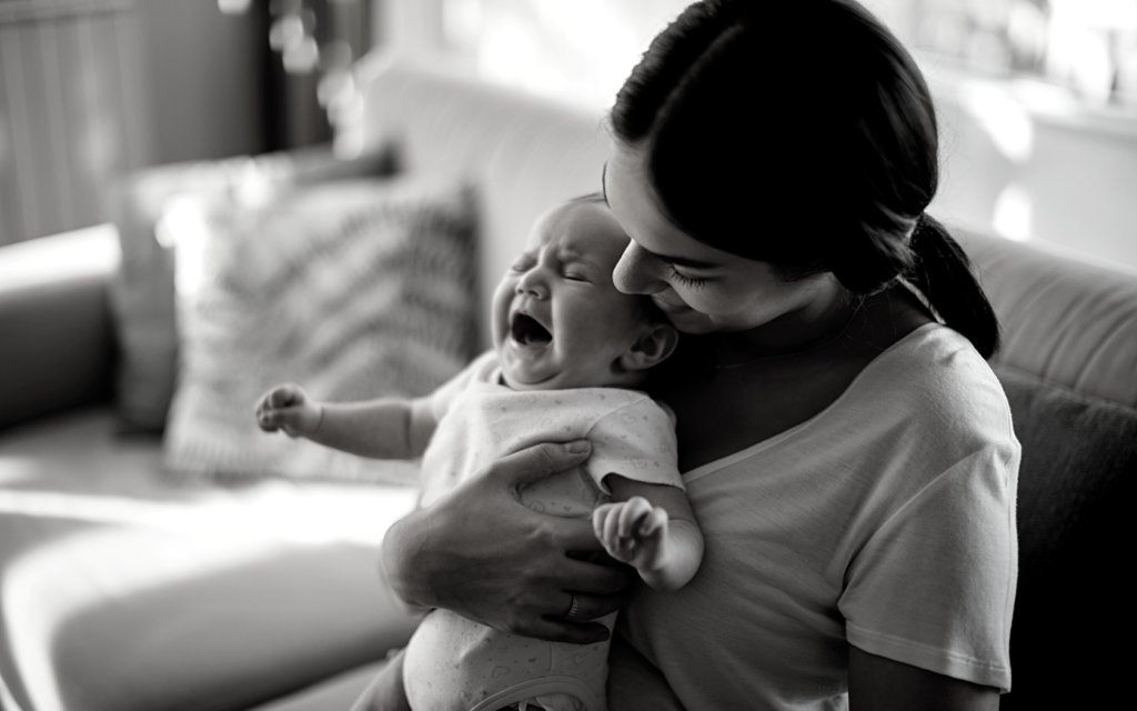 Mother holds her crying baby.