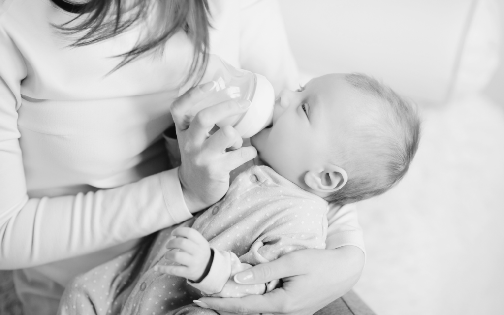 Mother feeds baby with bottle.