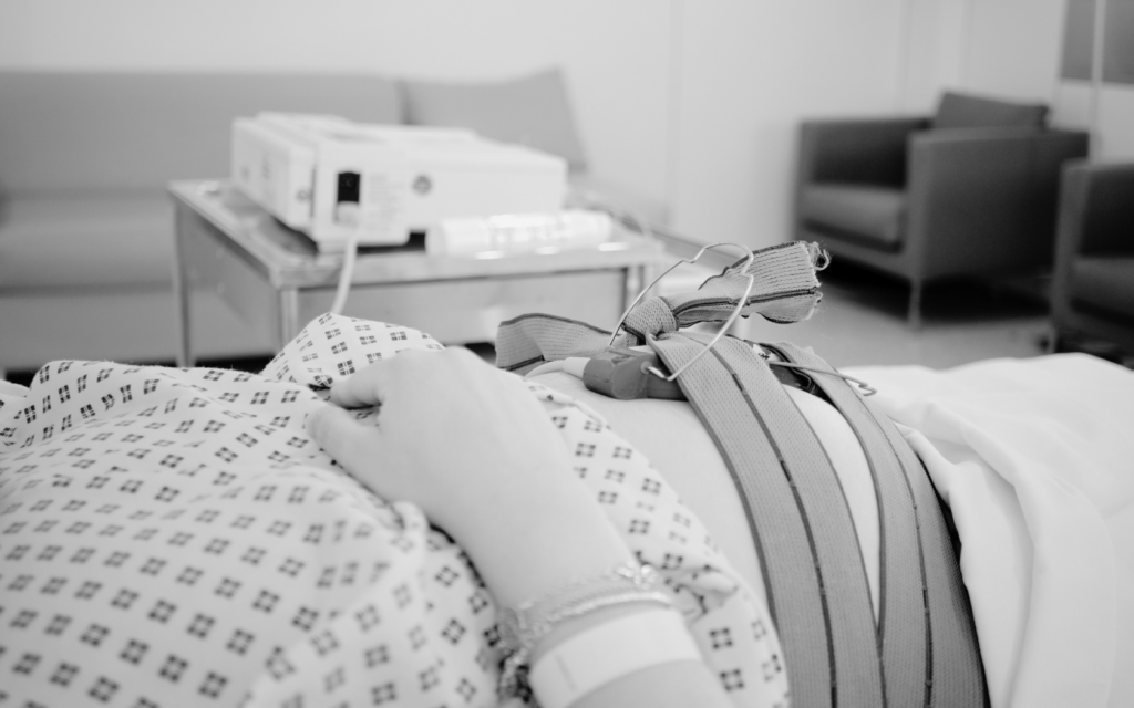 Pregnant woman in a hospital bed being monitored by medical equipment.