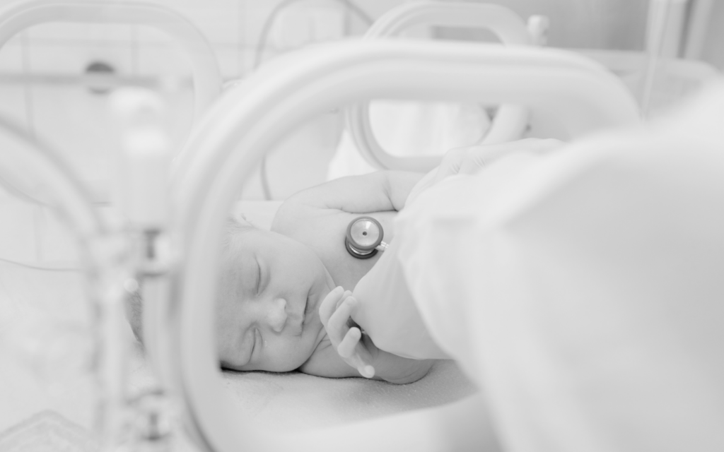A newborn baby receiving neonatal care, surrounded by medical equipment.